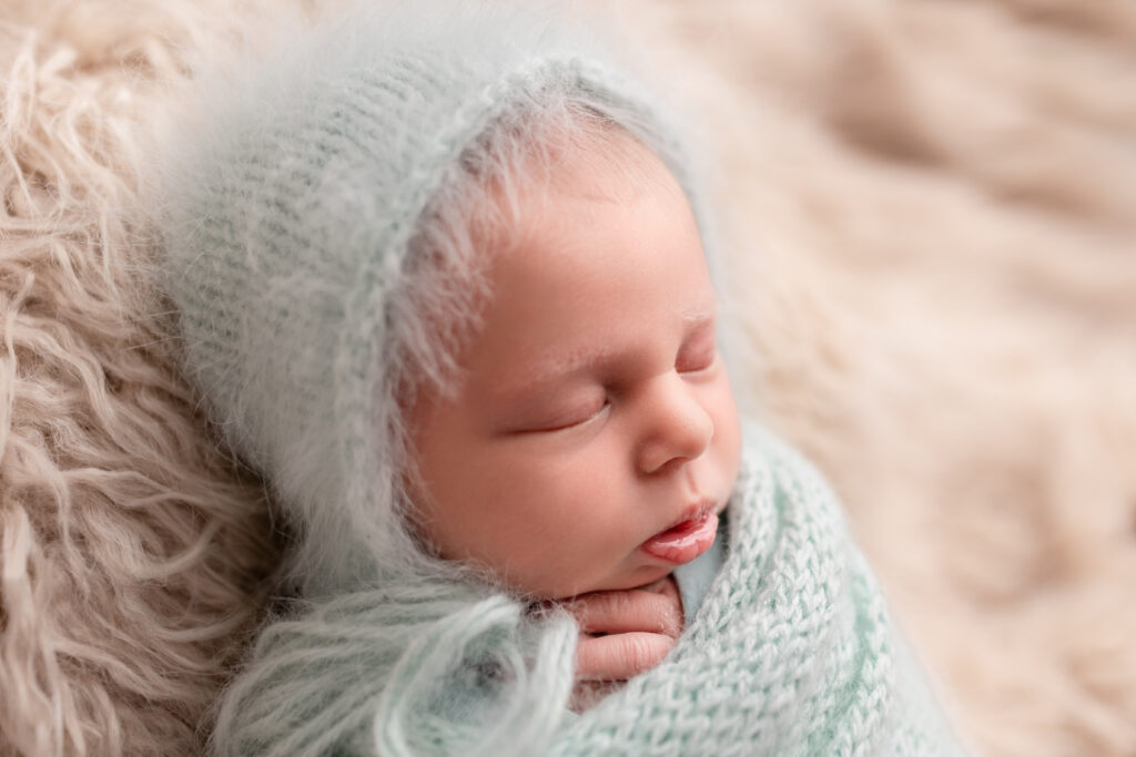 Baby girl wrapped in a knit wrap posed on a flokati during her in-home newborn photography session in Frankfort, Kentucky.
