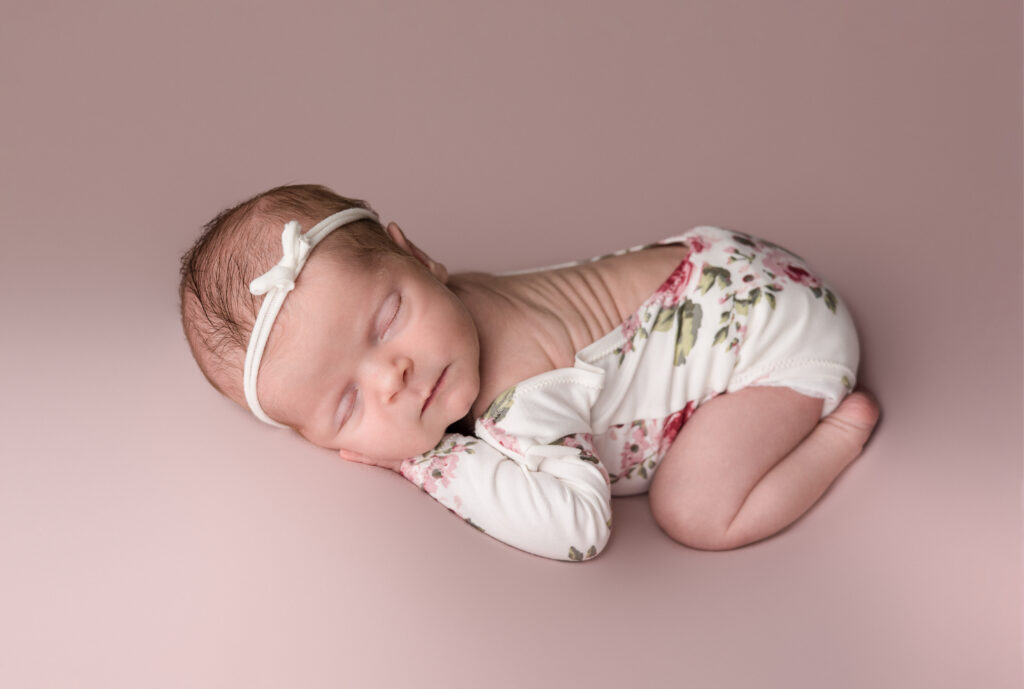 Baby girl posed on pink backdrop during an in-home newborn photography session in Frankfort, Kentucky.
