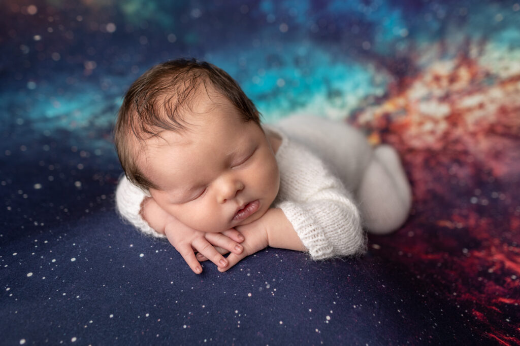 Baby boy posed on a space themed backdrop during his in-home newborn photography session in Frankfort, Kentucky.