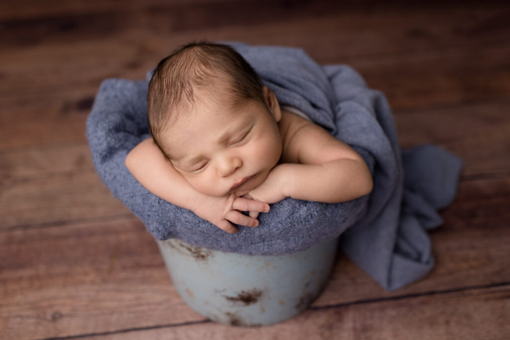 Baby boy posed in a blue bucket during his in-home newborn photography session in Frankfort, Kentucky.